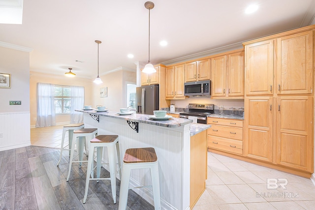 kitchen with pendant lighting, light brown cabinetry, a kitchen bar, a center island, and stainless steel appliances