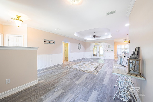 interior space with crown molding, hardwood / wood-style floors, a tray ceiling, and french doors