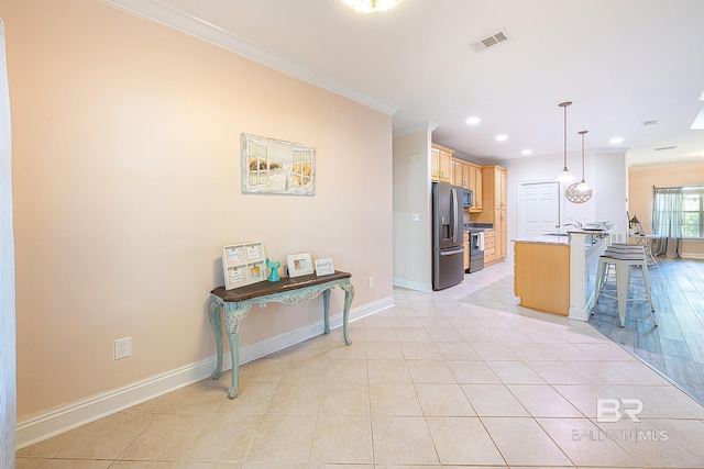 kitchen with appliances with stainless steel finishes, pendant lighting, a kitchen breakfast bar, ornamental molding, and light tile patterned floors