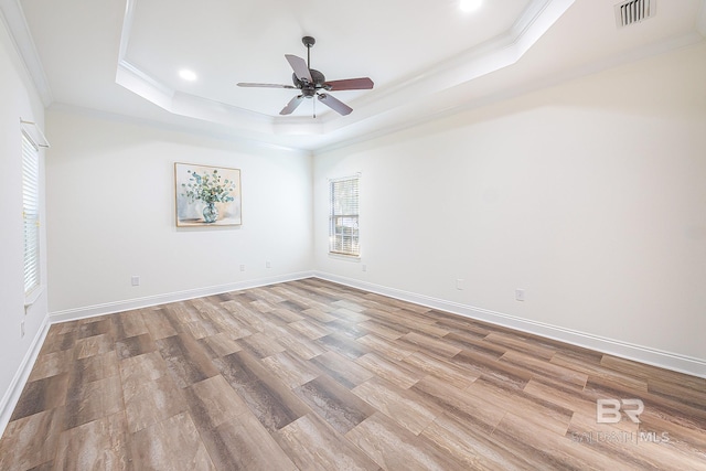 unfurnished room with crown molding, a tray ceiling, ceiling fan, and light wood-type flooring