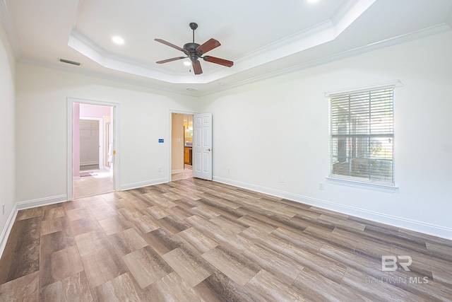 unfurnished room with crown molding, light hardwood / wood-style flooring, a raised ceiling, and ceiling fan