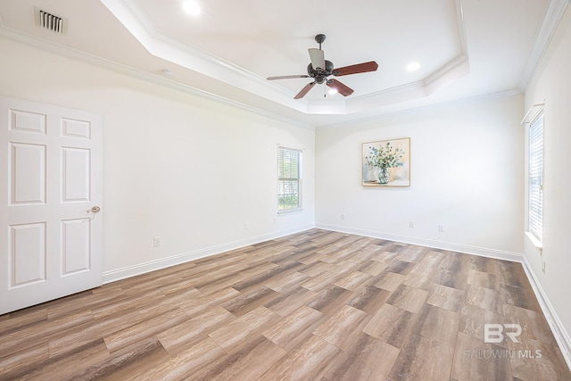 unfurnished room featuring crown molding, ceiling fan, a tray ceiling, and light hardwood / wood-style flooring