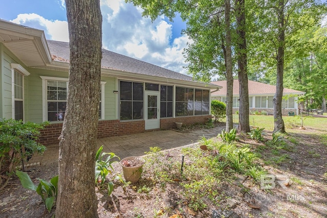 rear view of property featuring a sunroom and a patio area