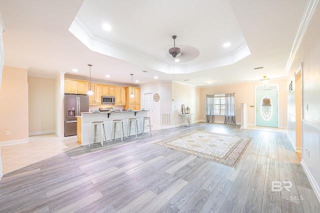 unfurnished living room featuring crown molding, a tray ceiling, light hardwood / wood-style floors, and ceiling fan