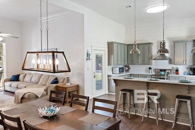 kitchen with a breakfast bar, pendant lighting, dark wood-type flooring, and stainless steel electric range