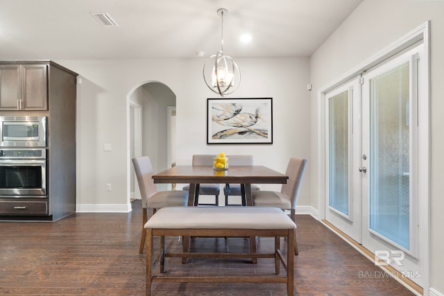 dining area featuring dark wood-type flooring and an inviting chandelier