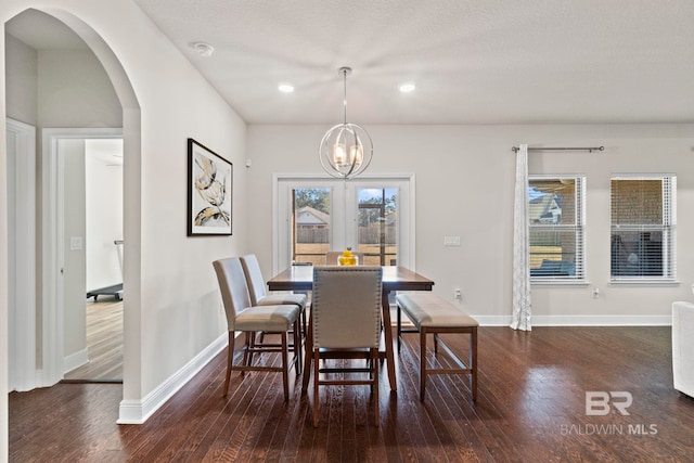 dining room with dark hardwood / wood-style floors, french doors, a textured ceiling, and an inviting chandelier