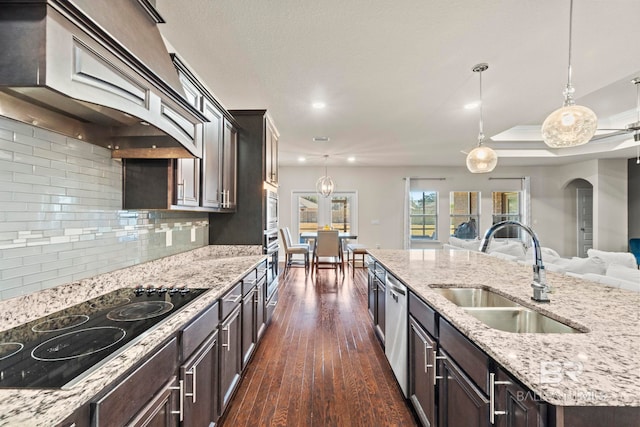 kitchen with custom exhaust hood, sink, hanging light fixtures, tasteful backsplash, and stainless steel appliances