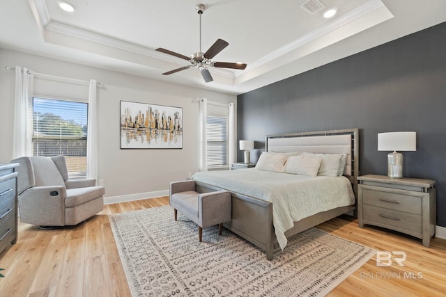 bedroom with a raised ceiling, ceiling fan, crown molding, and light hardwood / wood-style floors