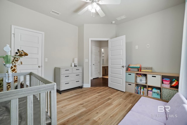 bedroom with ceiling fan, light hardwood / wood-style floors, and a crib