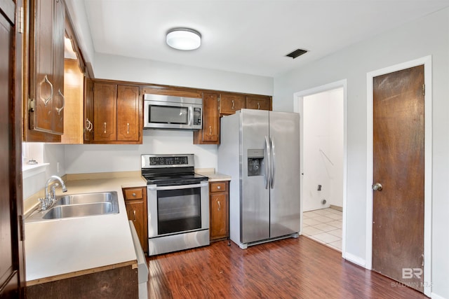 kitchen with appliances with stainless steel finishes, dark hardwood / wood-style floors, and sink