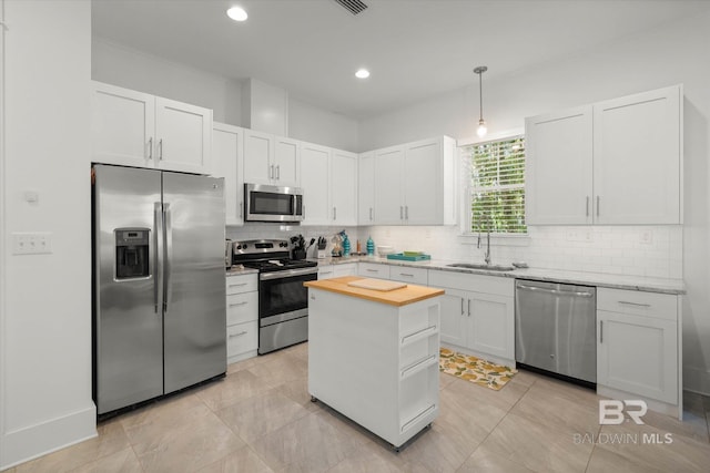 kitchen featuring backsplash, appliances with stainless steel finishes, a sink, and wooden counters