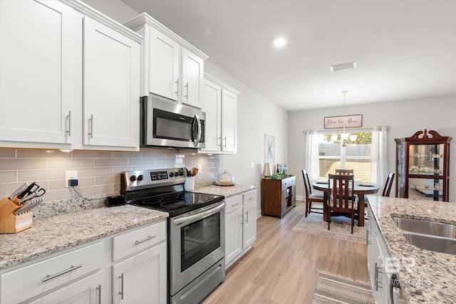 kitchen featuring decorative light fixtures, white cabinetry, appliances with stainless steel finishes, and a notable chandelier