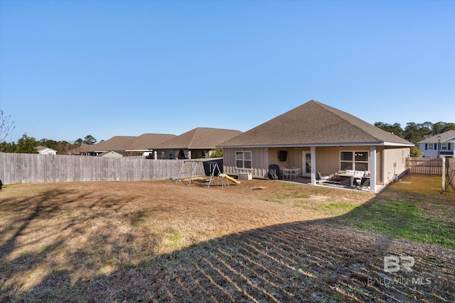 rear view of property with a playground, a yard, and a patio