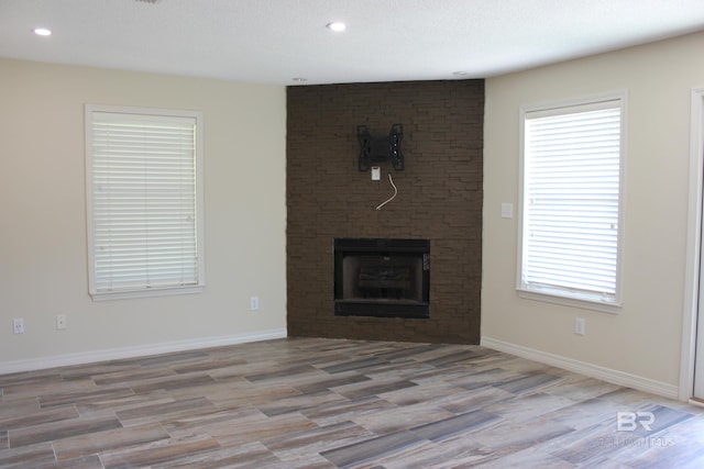 unfurnished living room with a fireplace, brick wall, and hardwood / wood-style floors