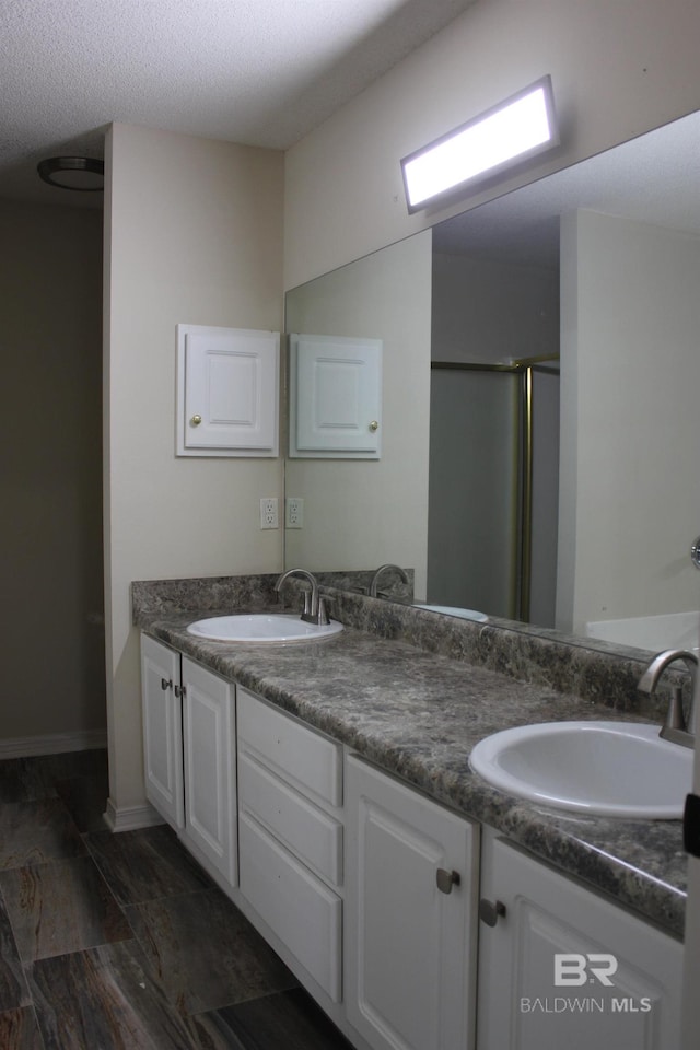 bathroom featuring dual bowl vanity, tile floors, and a textured ceiling