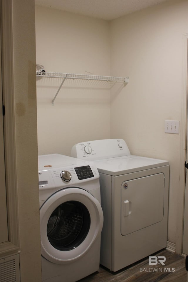 clothes washing area with hardwood / wood-style floors and washer and clothes dryer