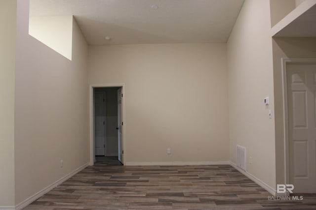 unfurnished room with a high ceiling and dark hardwood / wood-style floors