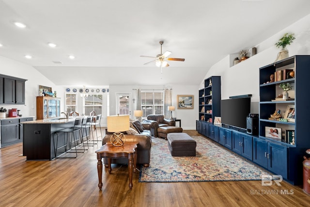 living room featuring built in shelves, ceiling fan, hardwood / wood-style floors, and vaulted ceiling