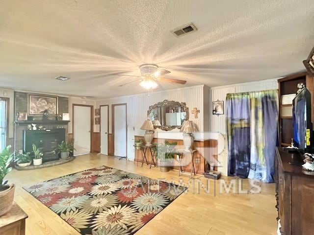 living room with ceiling fan, a textured ceiling, and hardwood / wood-style floors