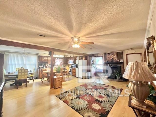 living room featuring light hardwood / wood-style floors, a textured ceiling, and ceiling fan