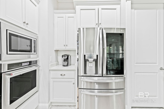 kitchen featuring white cabinetry, stainless steel appliances, light tile patterned flooring, and backsplash