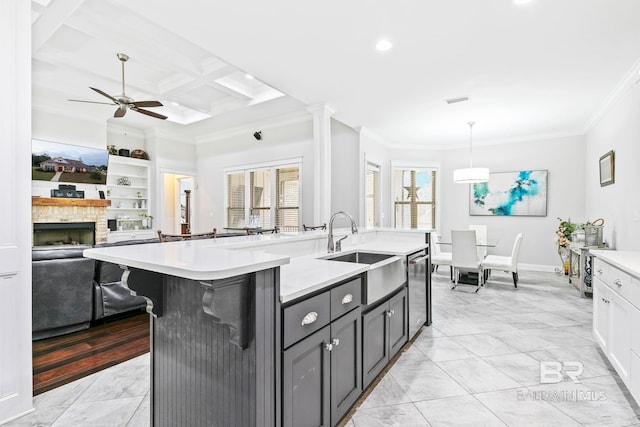 kitchen featuring ornamental molding, a fireplace, coffered ceiling, hanging light fixtures, and sink