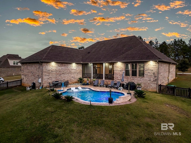 pool at dusk with a patio and a yard