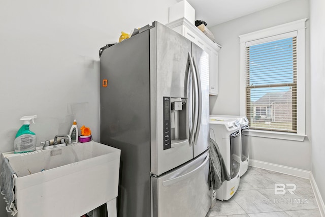 laundry area featuring washing machine and dryer, cabinets, sink, and light tile patterned floors