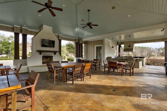 view of patio featuring ceiling fan, an outdoor fireplace, and a bar