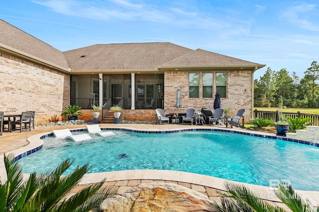 view of swimming pool featuring a sunroom, pool water feature, and a patio area