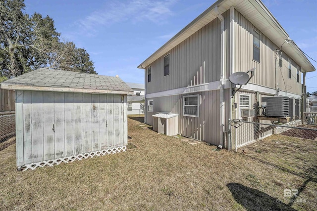 rear view of property with a shed, central air condition unit, and a yard