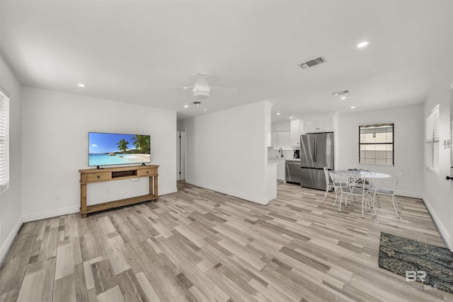 living room featuring ceiling fan, light hardwood / wood-style flooring, and sink