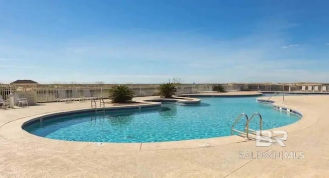 community pool with a patio area and fence