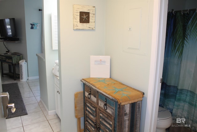 bathroom featuring tile patterned floors, toilet, baseboards, and a shower with curtain