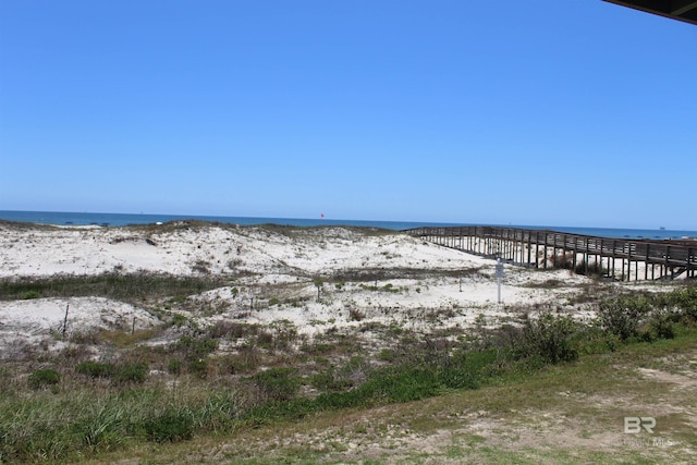 property view of water featuring a pier and a beach view