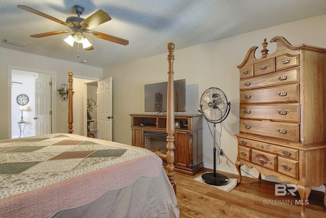 bedroom featuring light hardwood / wood-style flooring, a textured ceiling, and ceiling fan