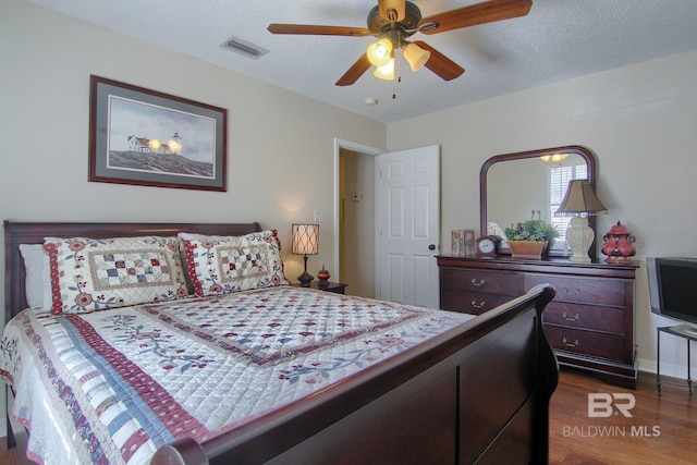 bedroom with a textured ceiling, dark hardwood / wood-style floors, and ceiling fan