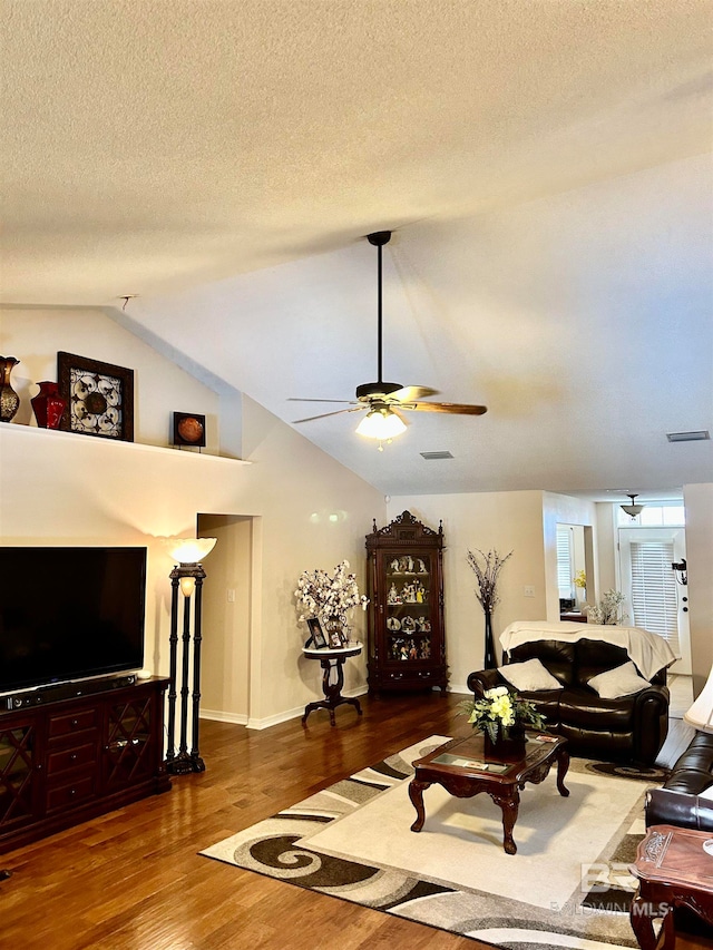 living room with dark hardwood / wood-style floors, ceiling fan, a textured ceiling, and vaulted ceiling