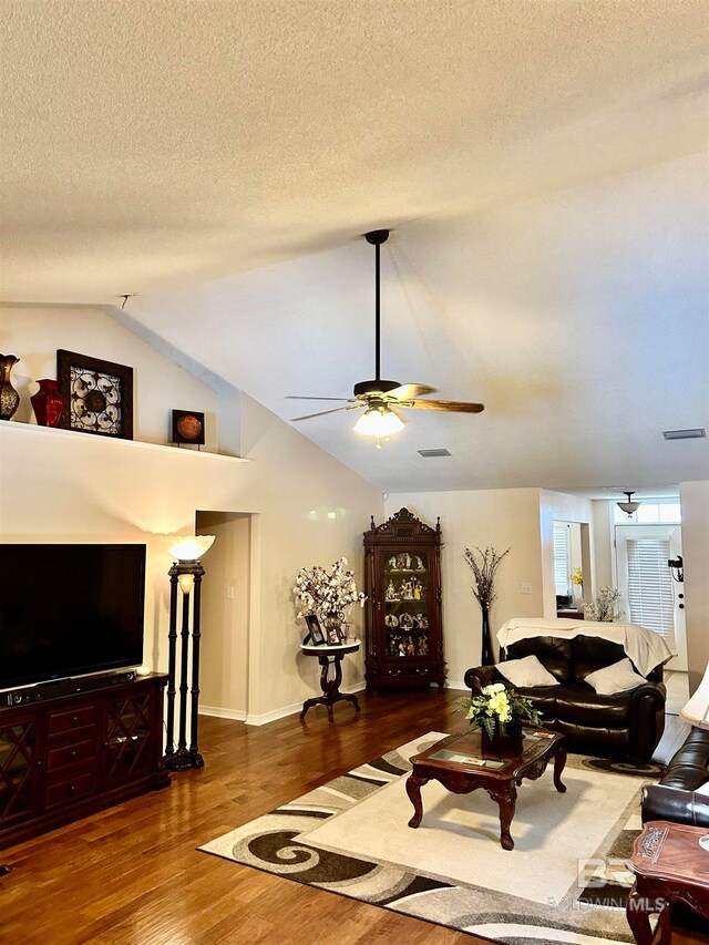 living room with ceiling fan, a textured ceiling, lofted ceiling, and dark hardwood / wood-style flooring