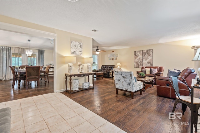 living room with ceiling fan, a textured ceiling, and light wood-type flooring