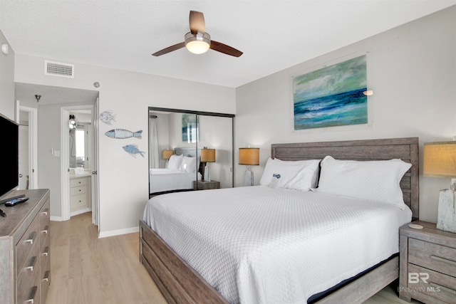 bedroom featuring ceiling fan, a closet, ensuite bathroom, and light wood-type flooring