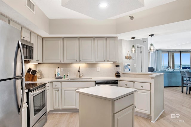 kitchen featuring sink, hanging light fixtures, stainless steel appliances, tasteful backsplash, and light hardwood / wood-style flooring