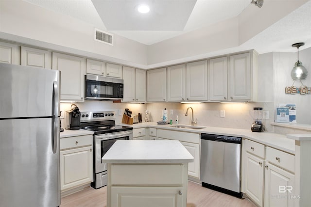 kitchen featuring sink, light hardwood / wood-style flooring, a textured ceiling, decorative light fixtures, and stainless steel appliances