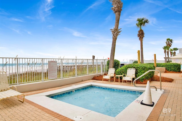 view of swimming pool with a water view and a beach view