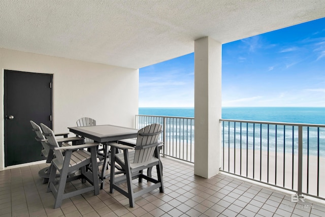 balcony with a water view and a view of the beach