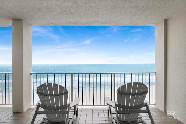 balcony with a water view and a view of the beach