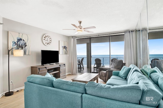 living room with a wealth of natural light, ceiling fan, light hardwood / wood-style floors, and a textured ceiling