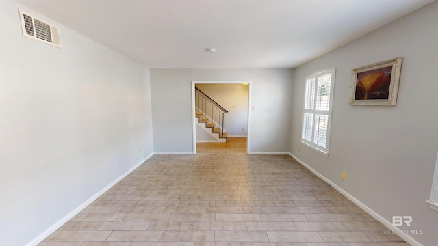 unfurnished room featuring stairs, baseboards, and visible vents