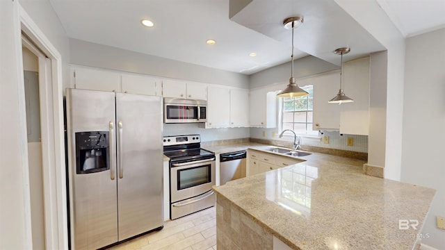 kitchen with backsplash, appliances with stainless steel finishes, a sink, white cabinets, and a peninsula